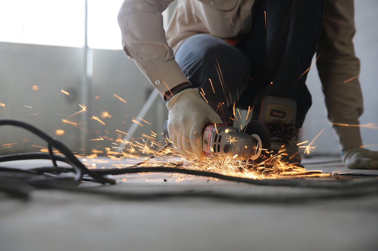 Home A skilled industrial worker uses a grinder creating a burst of sparks indoors.