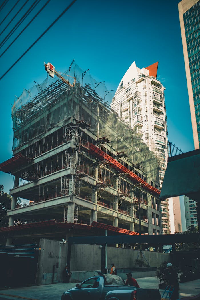 Home High-rise building under construction with scaffolding and crane in urban cityscape.